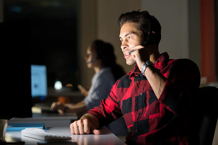 Portrait of male customer service operator working at night using headset, copy space